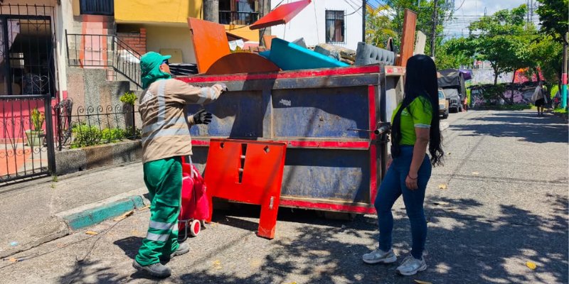 Operario de Atesa y promotora de la Empresa de Aseo de Pereira junto a la caja estacionaria llena de inservibles